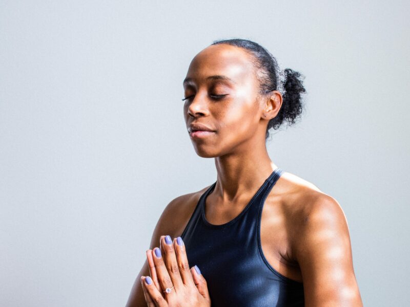 Black woman with eyes closed and hands together practices yoga